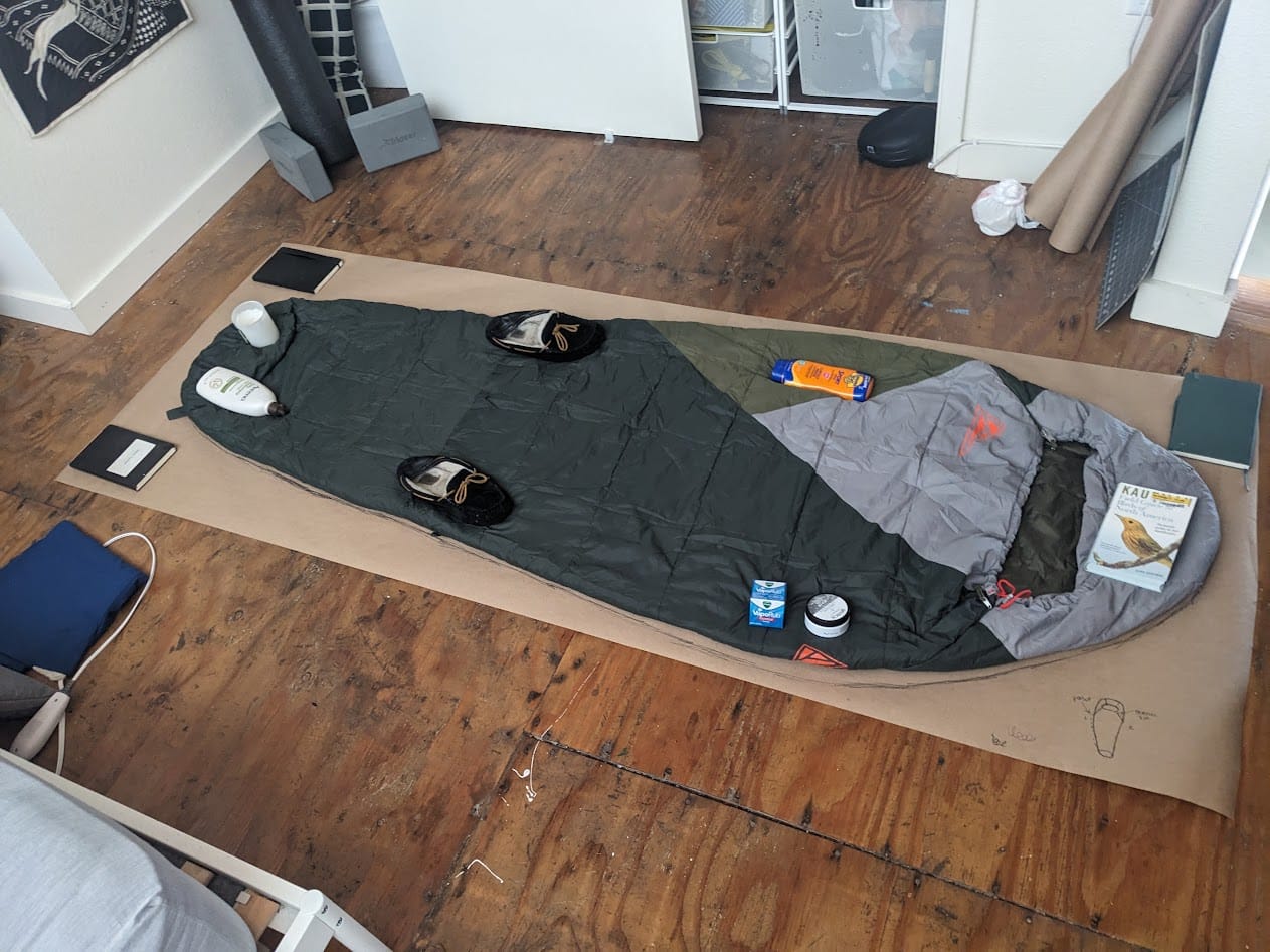 sleeping bag on a piece of brown kraft paper, held down for tracing by various household objects