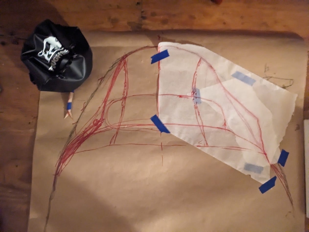 closeup of the hood portion of the paper pattern, with lots of overlapping sketch lines and some trace paper