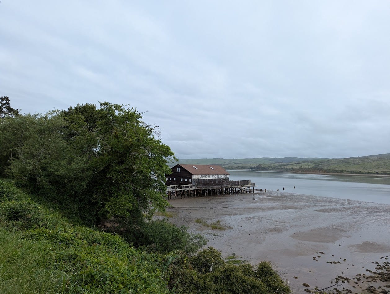 tomales bay, cloudy, at low tide. a dock building with "launch for hire" painted on the side