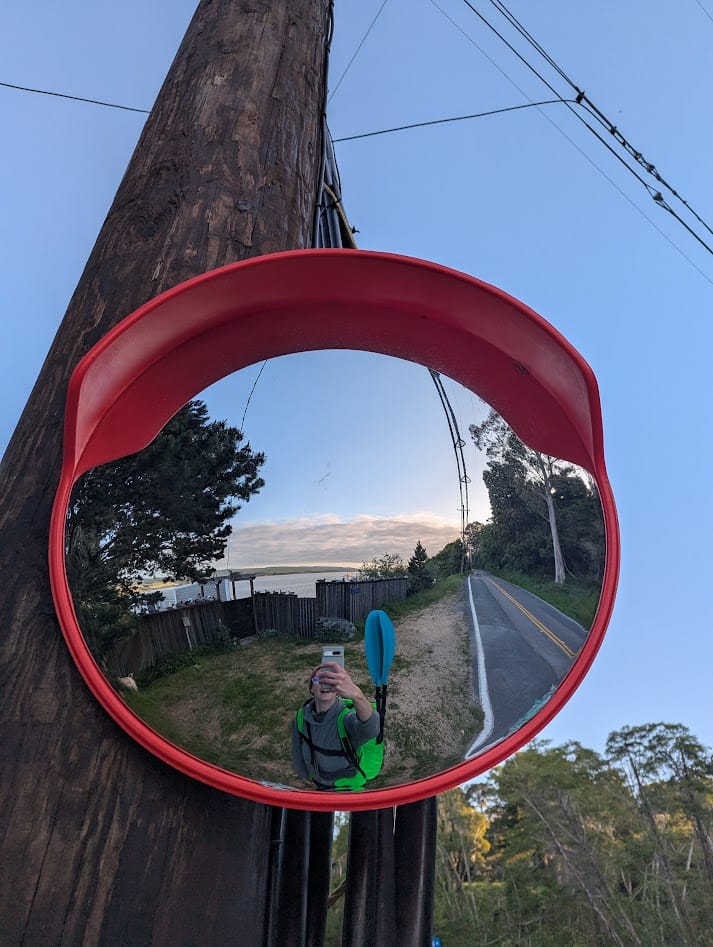 me with my boatpack, along a 2-lane highway, taking a selfie in a convex mirror