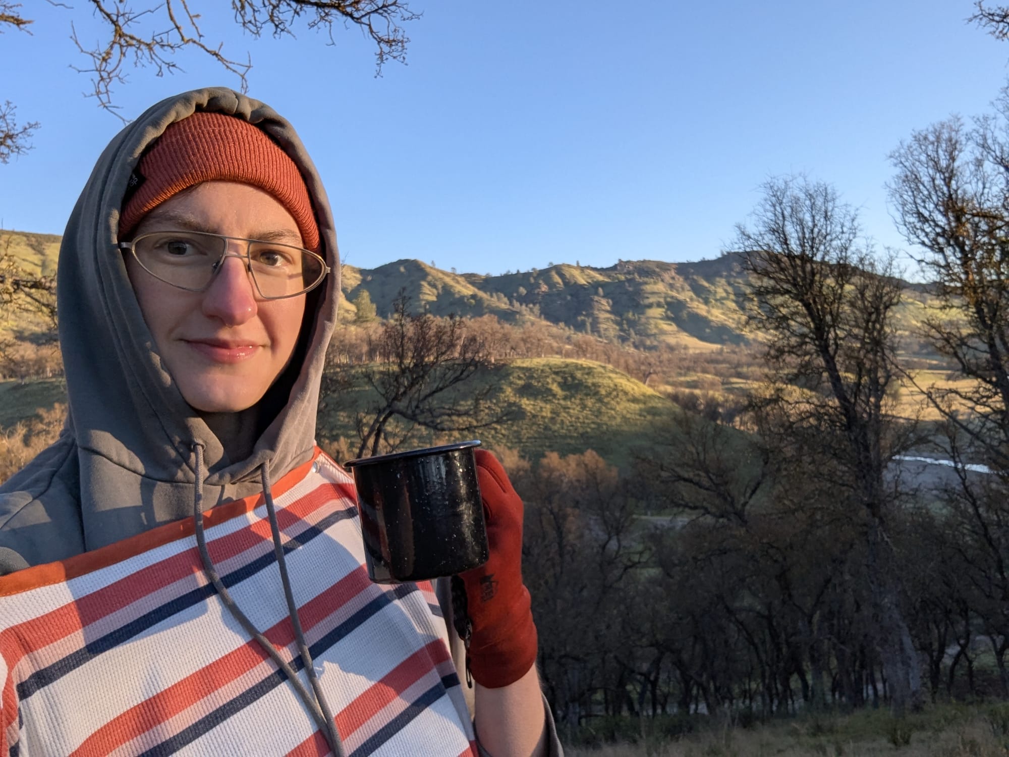 me smiling, holding a coffee cup, wearing the bag liner over layers of warm clothing