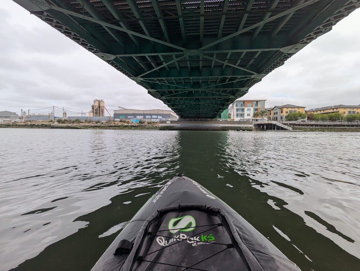 kayak under a green metal bridge