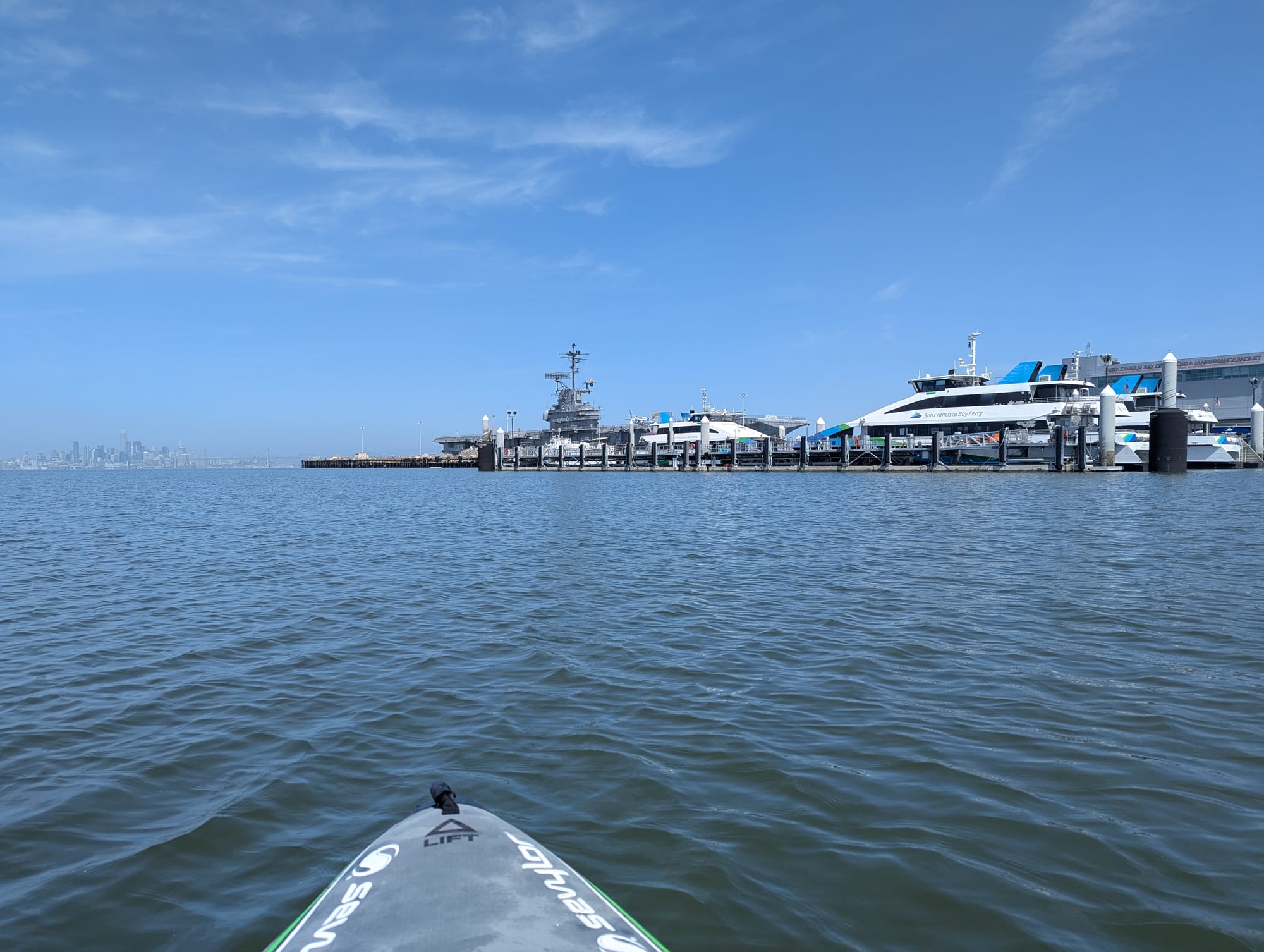 my boat approaching a dock with several large ferries. the top of the Hornet and the SF skyline were visible in the background.