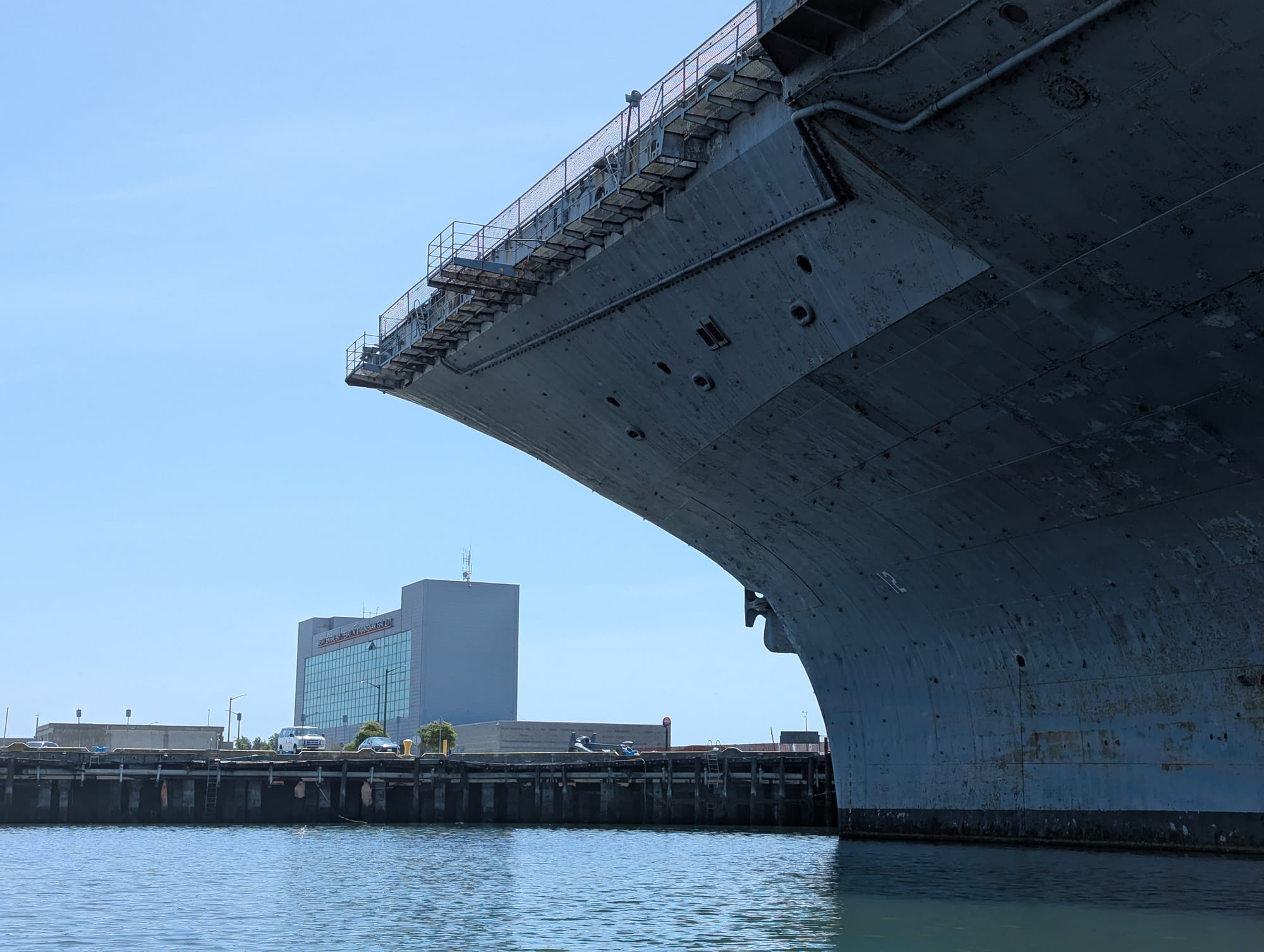 the side of the ship curving over a building on shore