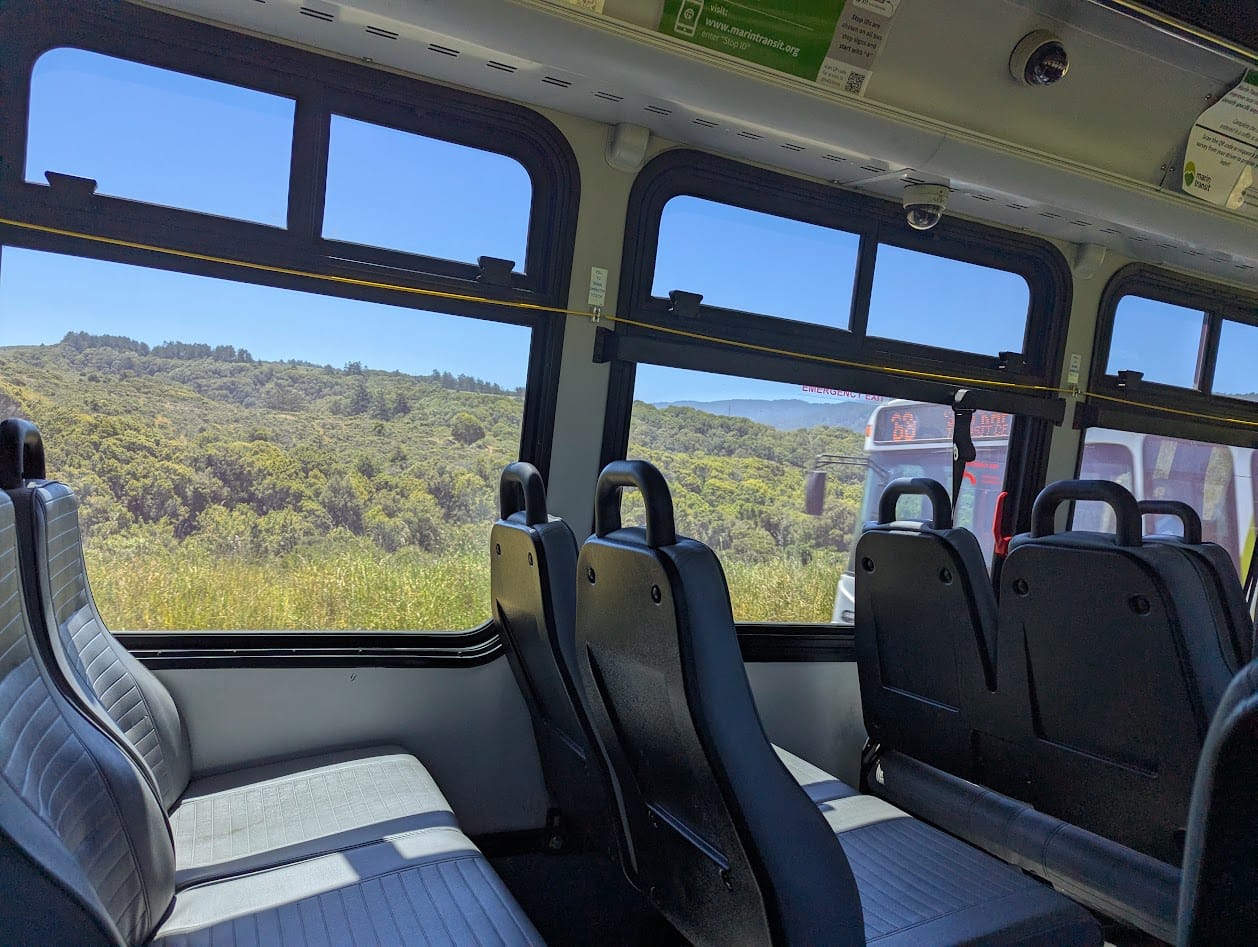 inside of a bus, passing another bus, on a road through coastal mountains