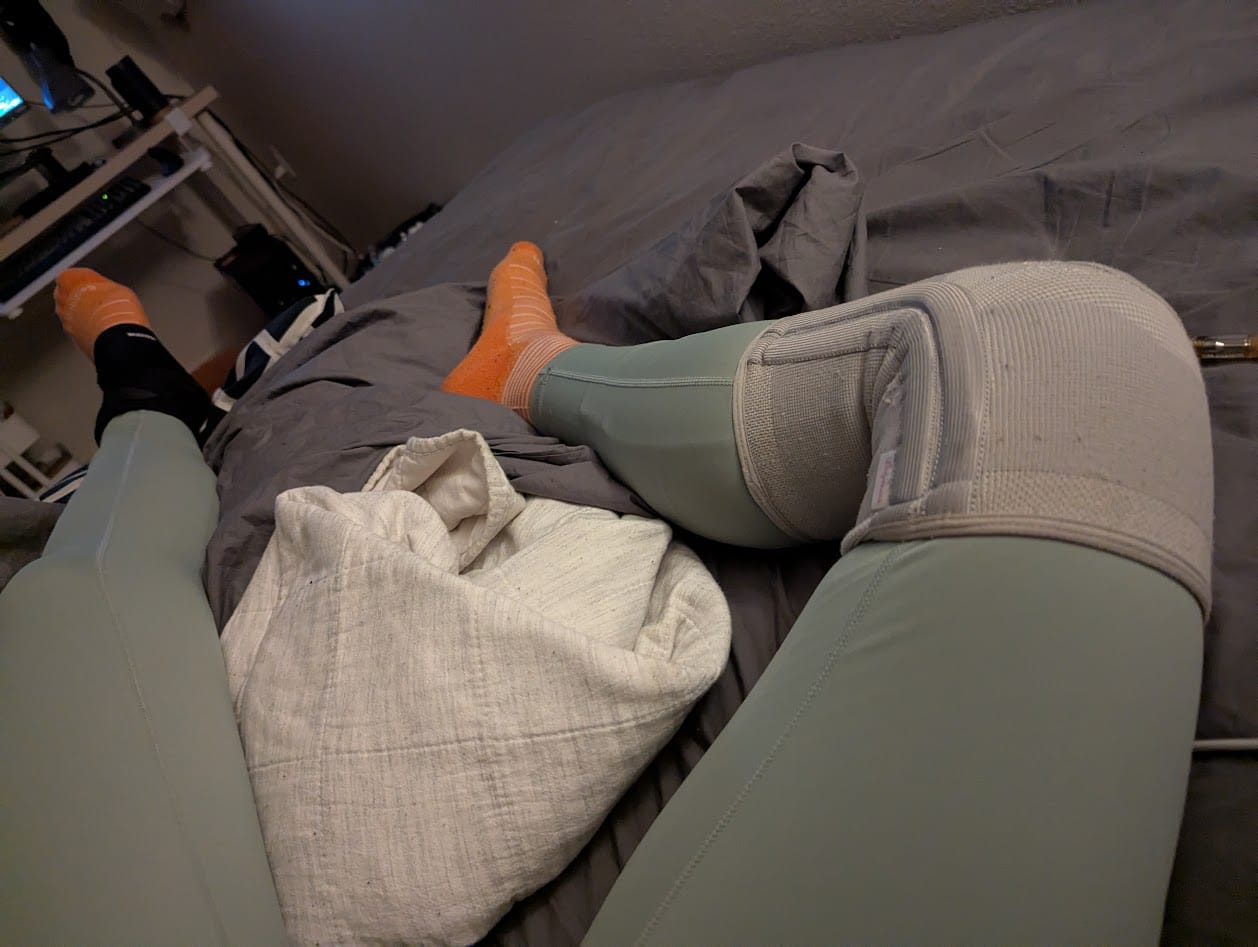 my legs in bed with a variety of braces on my knees and ankles, and compression socks