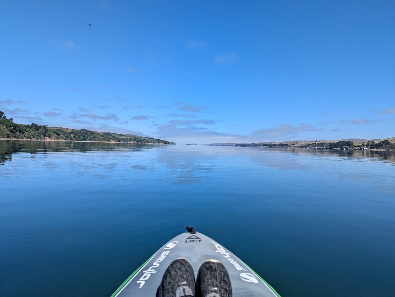 the front of my boat, calm water, blue sky, and dissipating clouds 