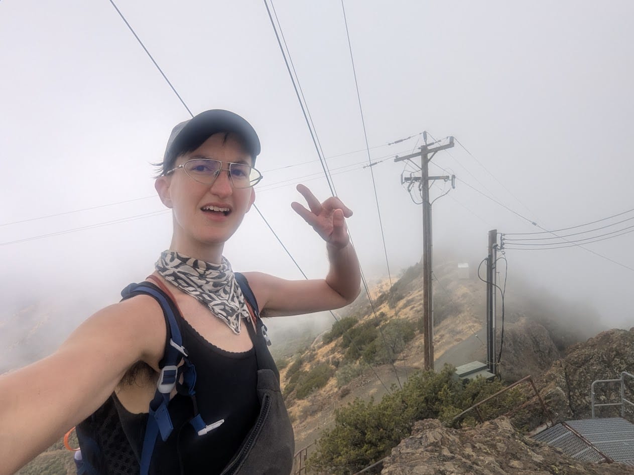me on a foggy hill looking exasperated and holding up 2 fingers