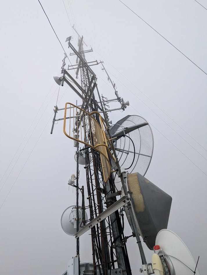 bunch of equipment on a radio tower in the clouds