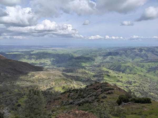 some fluffy clouds over a scenic vista of green hills