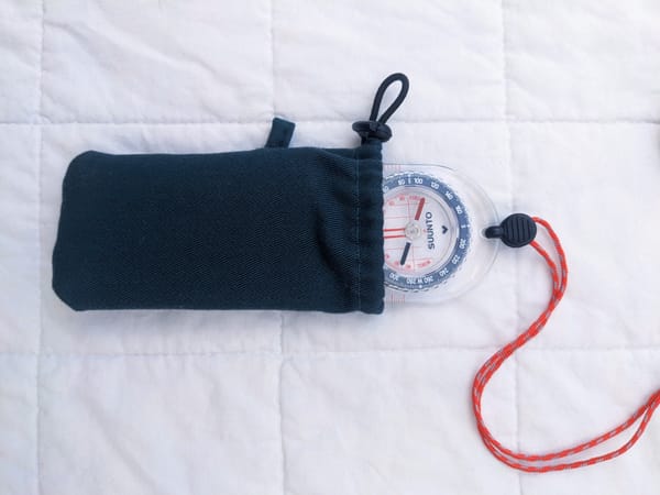 compass peeking out of a small green drawstring pouch